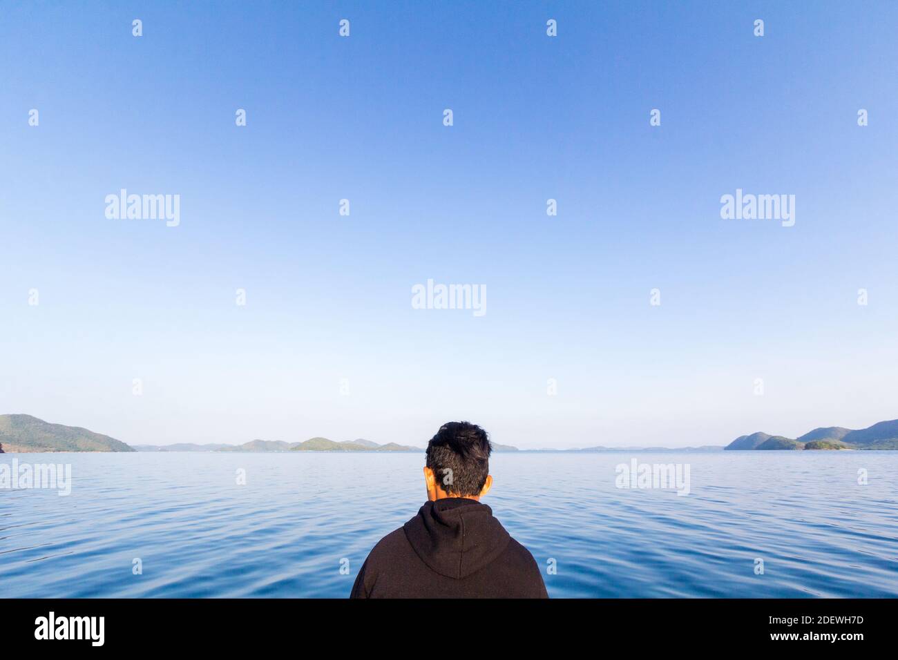 Un ragazzo che guarda l'ampia distesa di mare e cielo di un'isola di Palawan, Filippine Foto Stock