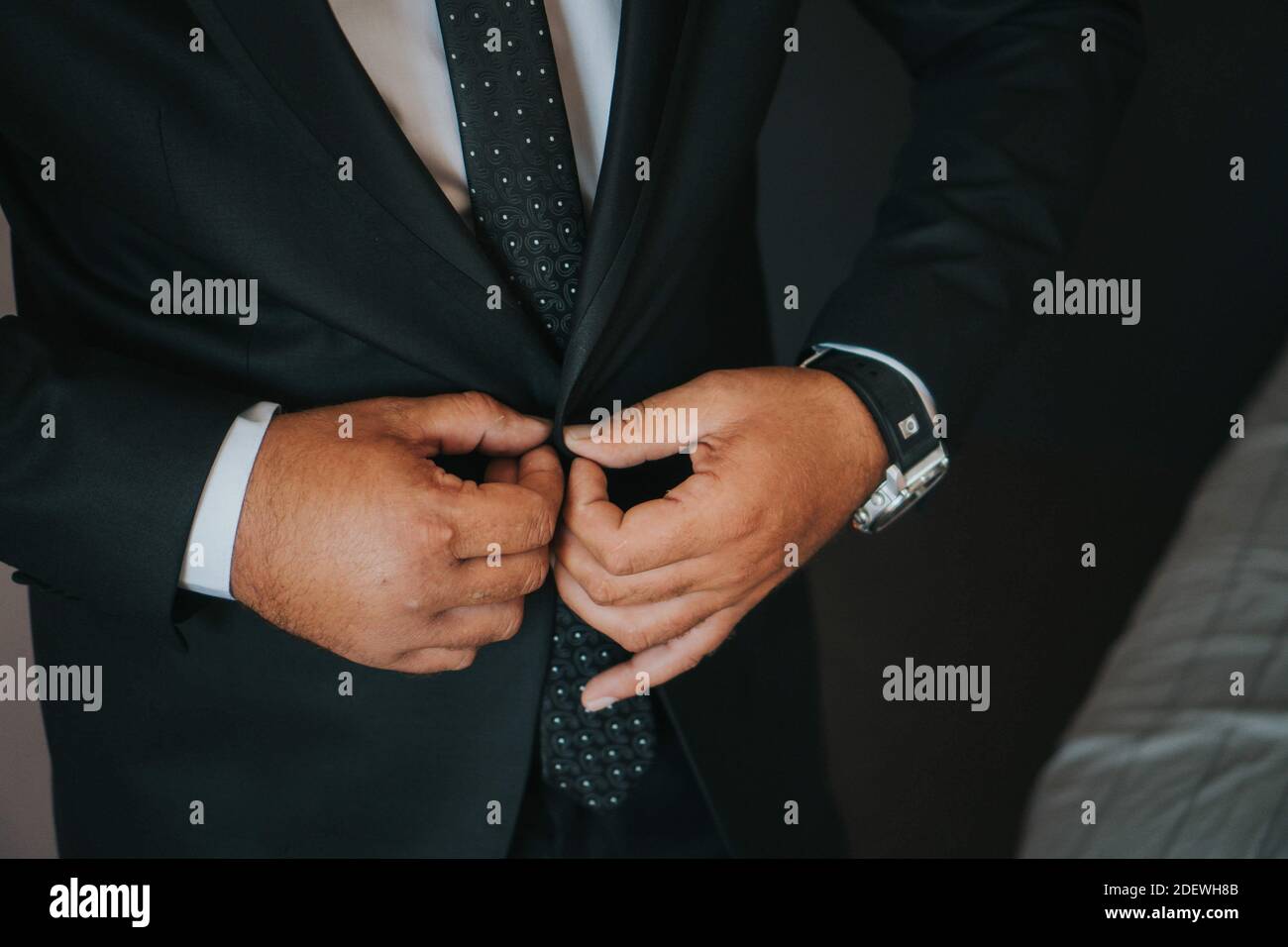 Un primo piano di una persona che indossa un abito formale abbottonando la sua tuta Foto Stock