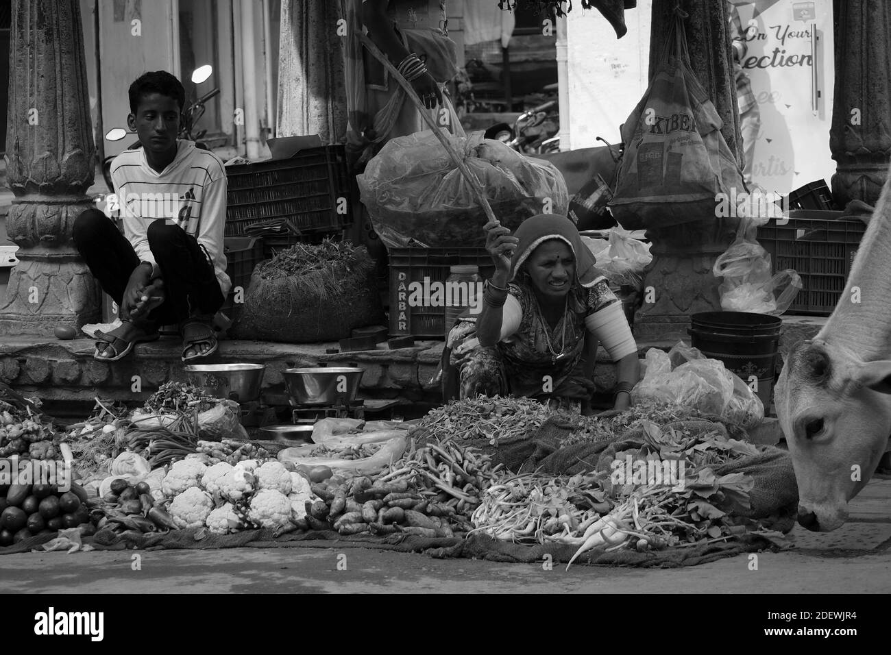 I venditori stanno aspettando i clienti e cercano di impedire alle mucche di mangiare la merce a Jaisalmer, India. Foto Stock