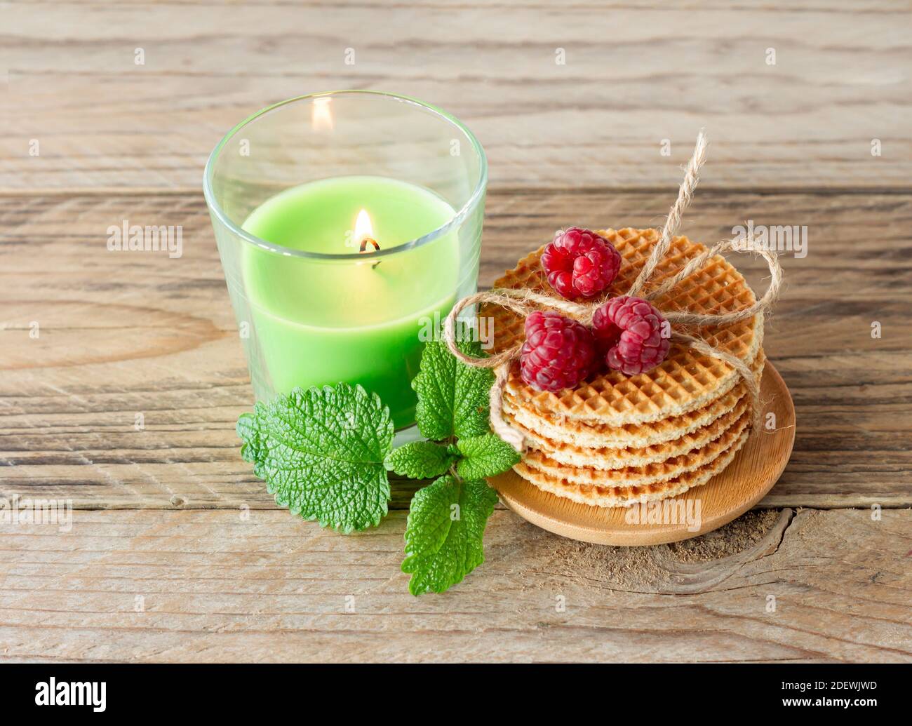 Pila di cialde tonde olandesi al caramello con lamponi su legno tavolo con  candela Foto stock - Alamy