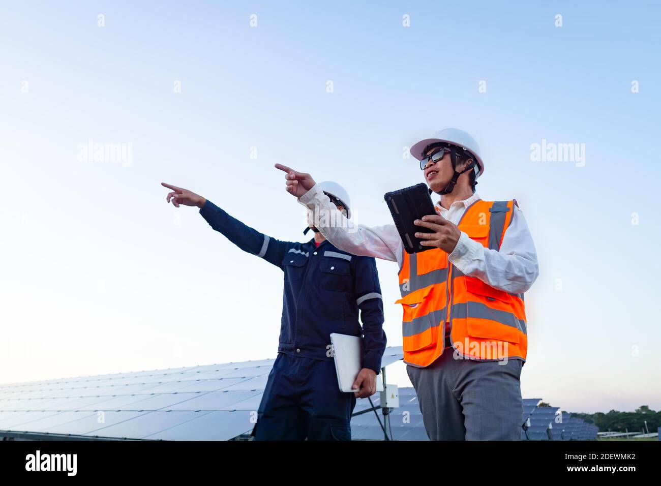 Ingegneri con investitore a piedi per controllare il funzionamento dei sistemi di fattoria solare (pannello solare), energia alternativa per conservare il mondo è energia, Photov Foto Stock