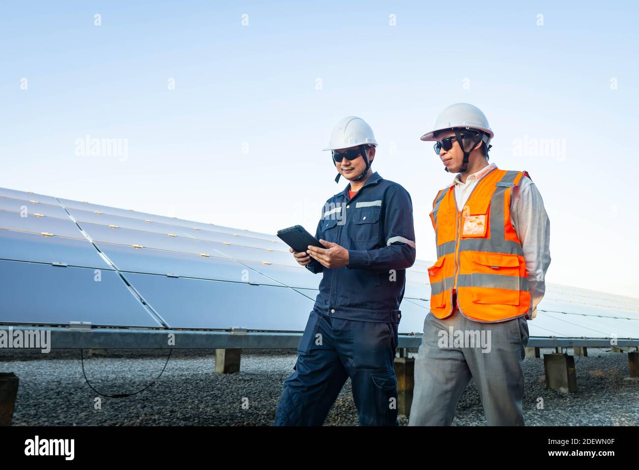Ingegneri con investitore a piedi per controllare il funzionamento dei sistemi di fattoria solare (pannello solare), energia alternativa per conservare il mondo è energia, Photov Foto Stock