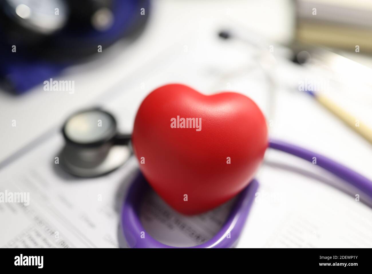 Stetoscopio e cuore rosso sul tavolo dell'ufficio medico. Foto Stock