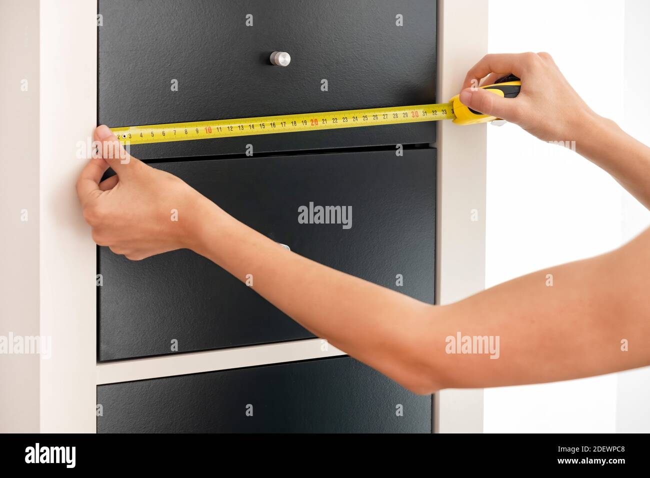 Le mani femminili misurano la larghezza dei cassetti con un automatico Metro a nastro Foto Stock