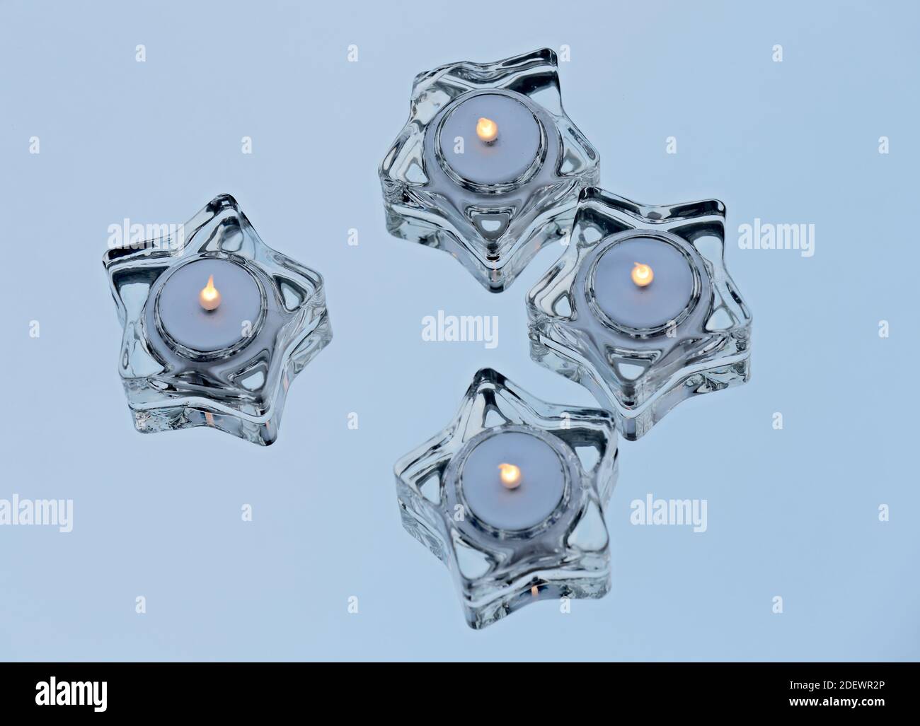 Quattro luci LED in vetro a forma di stella che bruciano su uno specchio Foto Stock
