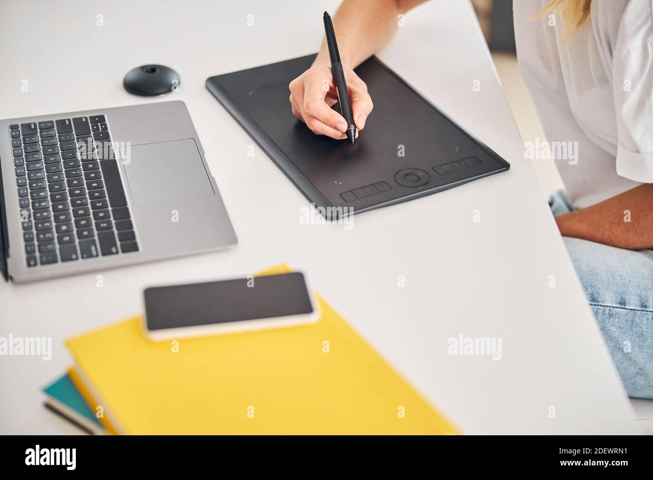 Artista femminile che utilizza un gadget per la creazione di disegni digitali Foto Stock