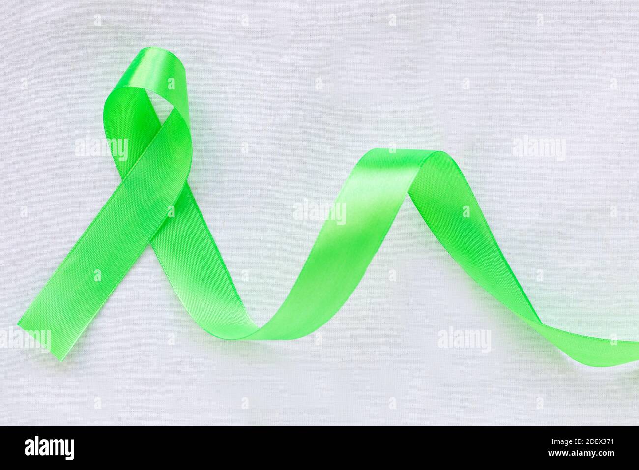 Il nastro verde smeraldo o verde giada si arriccia su sfondo rosa pastello  con spazio copia, simbolo per la consapevolezza del cancro al fegato,  Giornata Mondiale del cancro. Assistenza sanitaria o Foto