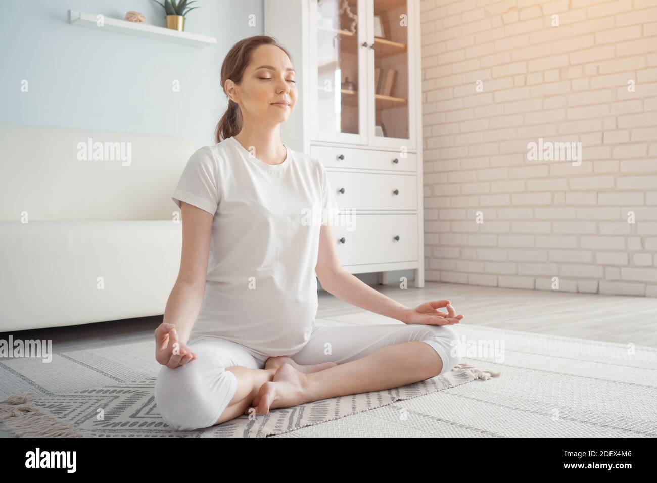Prevedendo la mamma che fa l'esercitazione di yoga in gravidanza copyspace vista laterale Foto Stock