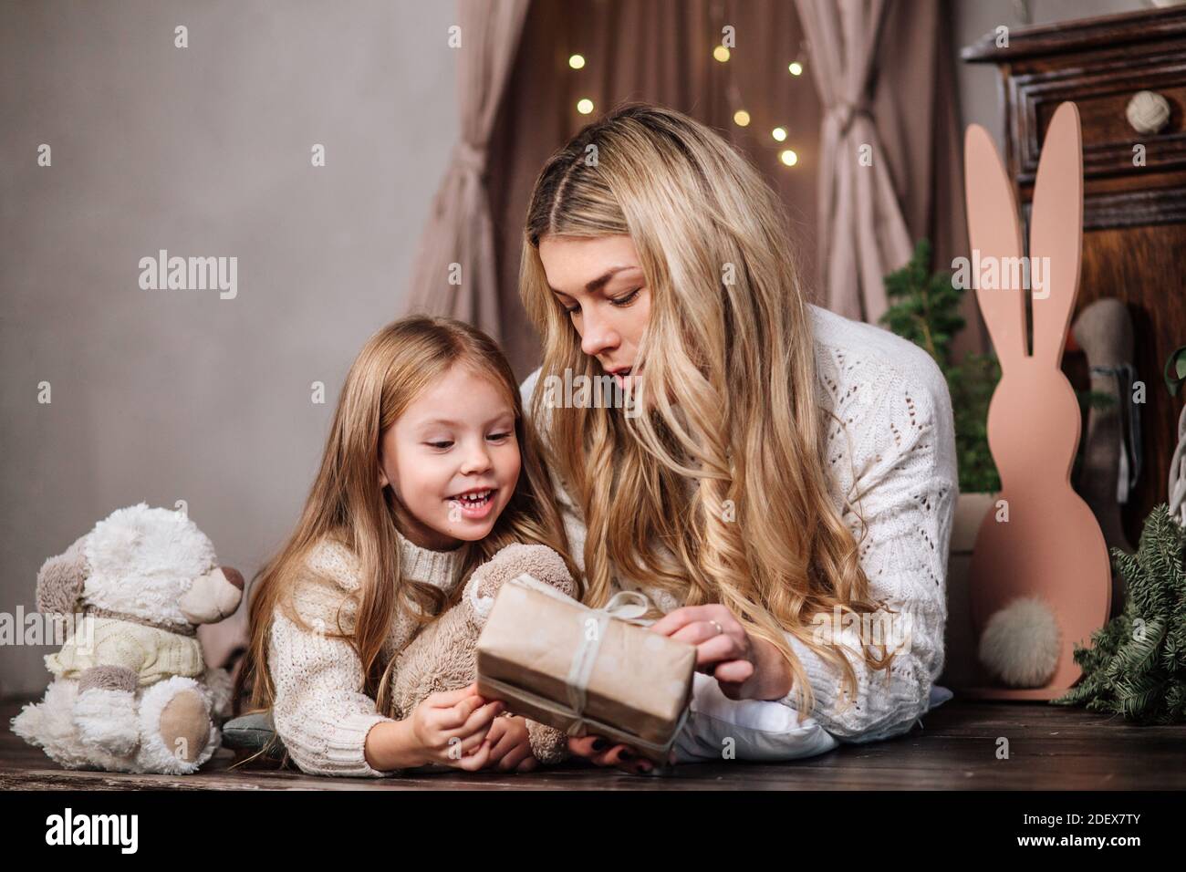 Buona madre e piccola figlia che aprono i regali di Natale Foto Stock