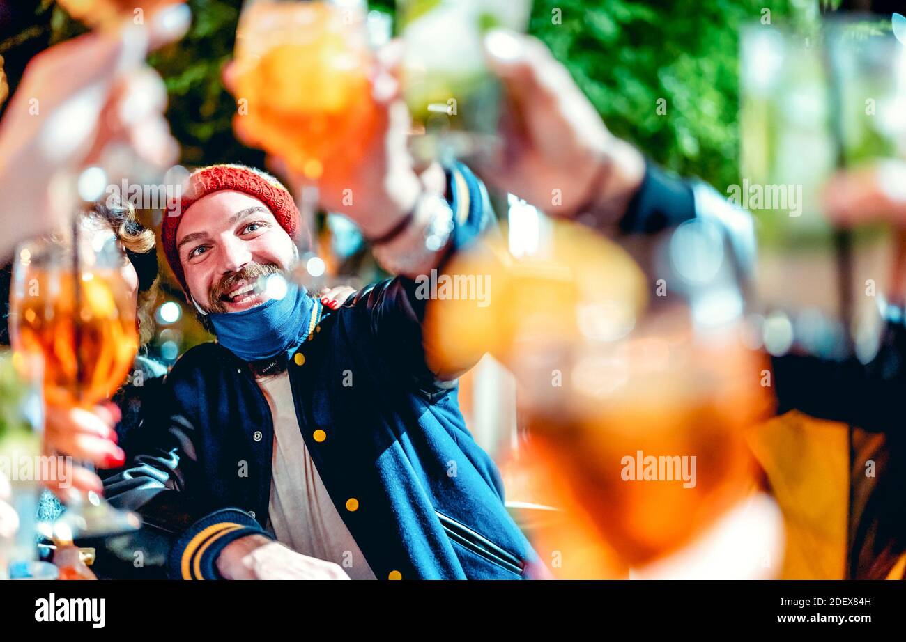 Happy guy tostando delle bevande di lusso al bar notturno con aperto Maschera - nuovo concetto di stile di vita normale con gli amici che si divertono insieme su abiti invernali Foto Stock