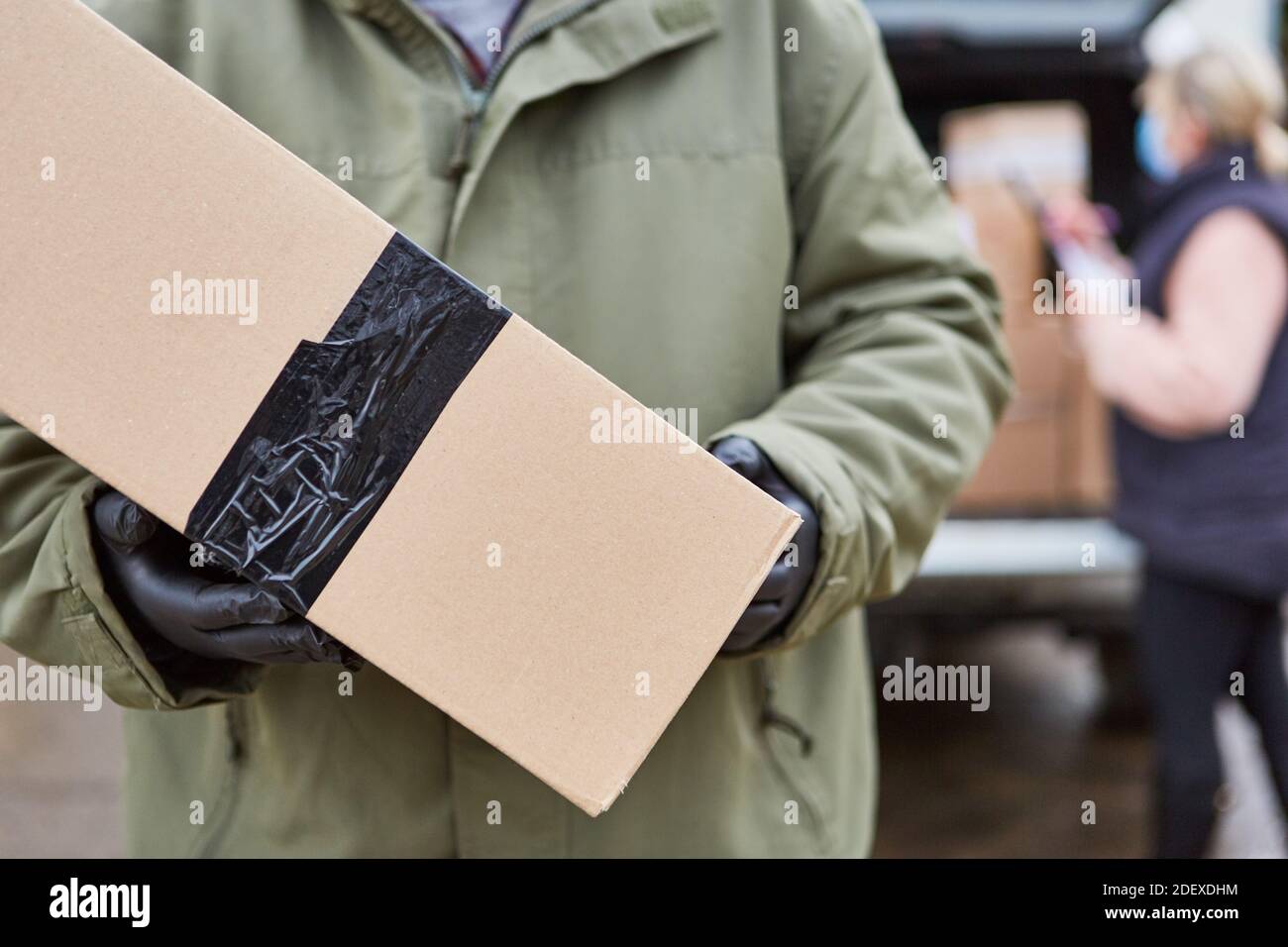 Mani di uomo di consegna del pacco che consegna il pacco a casa per Natale Foto Stock