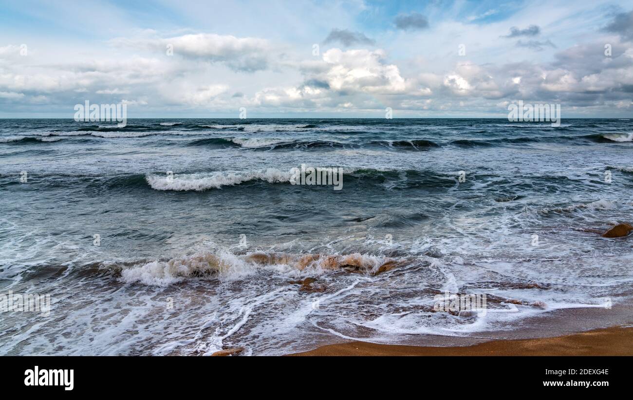 Spiaggia vuota e mare tempestoso in tempo nuvoloso Foto Stock