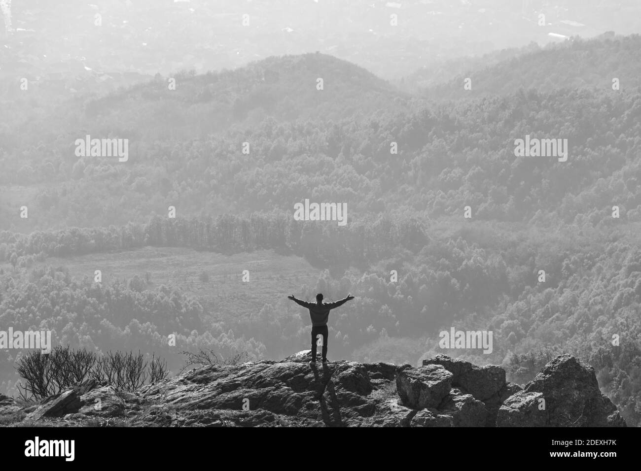 Giovane uomo in piedi sulla cima della montagna in sole giornate autunnali. Foto in bianco e nero Foto Stock