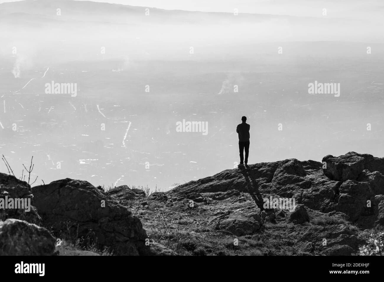 Giovane uomo in piedi sulla cima della montagna in sole giornate autunnali. Foto in bianco e nero Foto Stock