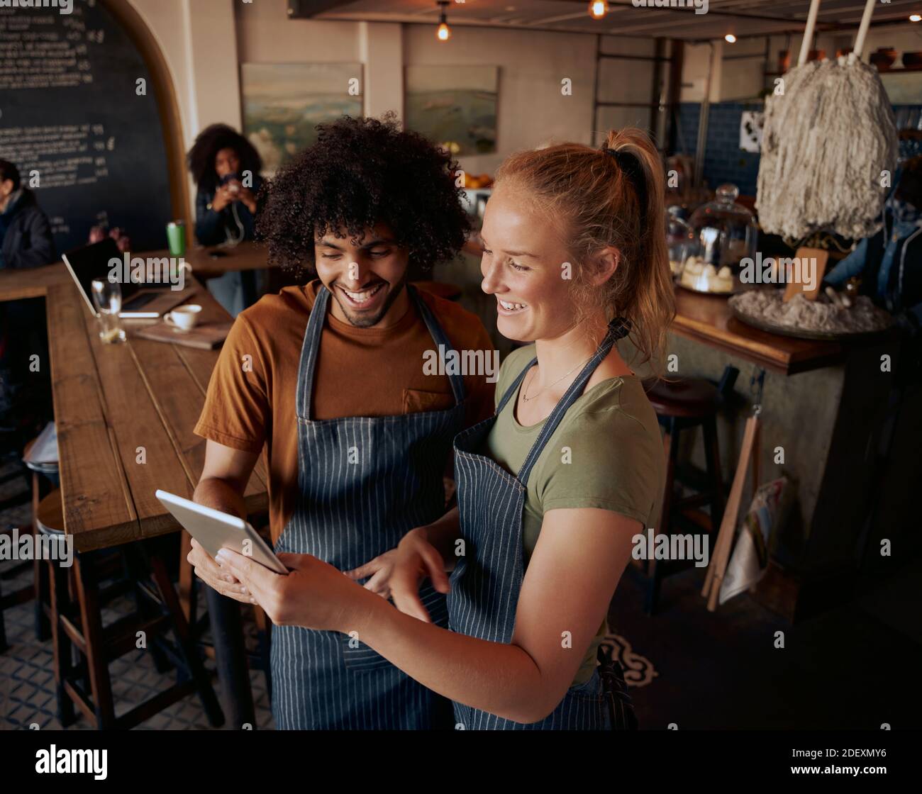 Vista ad alto angolo dei giovani proprietari di cafe' in piedi usando il digitale compressa con grembiule Foto Stock