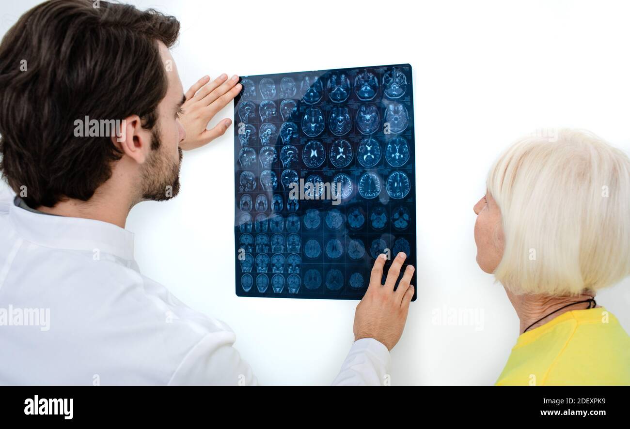 Il medico mostra a una donna anziana i risultati della risonanza magnetica del suo cervello. Diagnostica e trattamento di malattie cerebrali, mal di testa, tumori e cance cerebrali Foto Stock