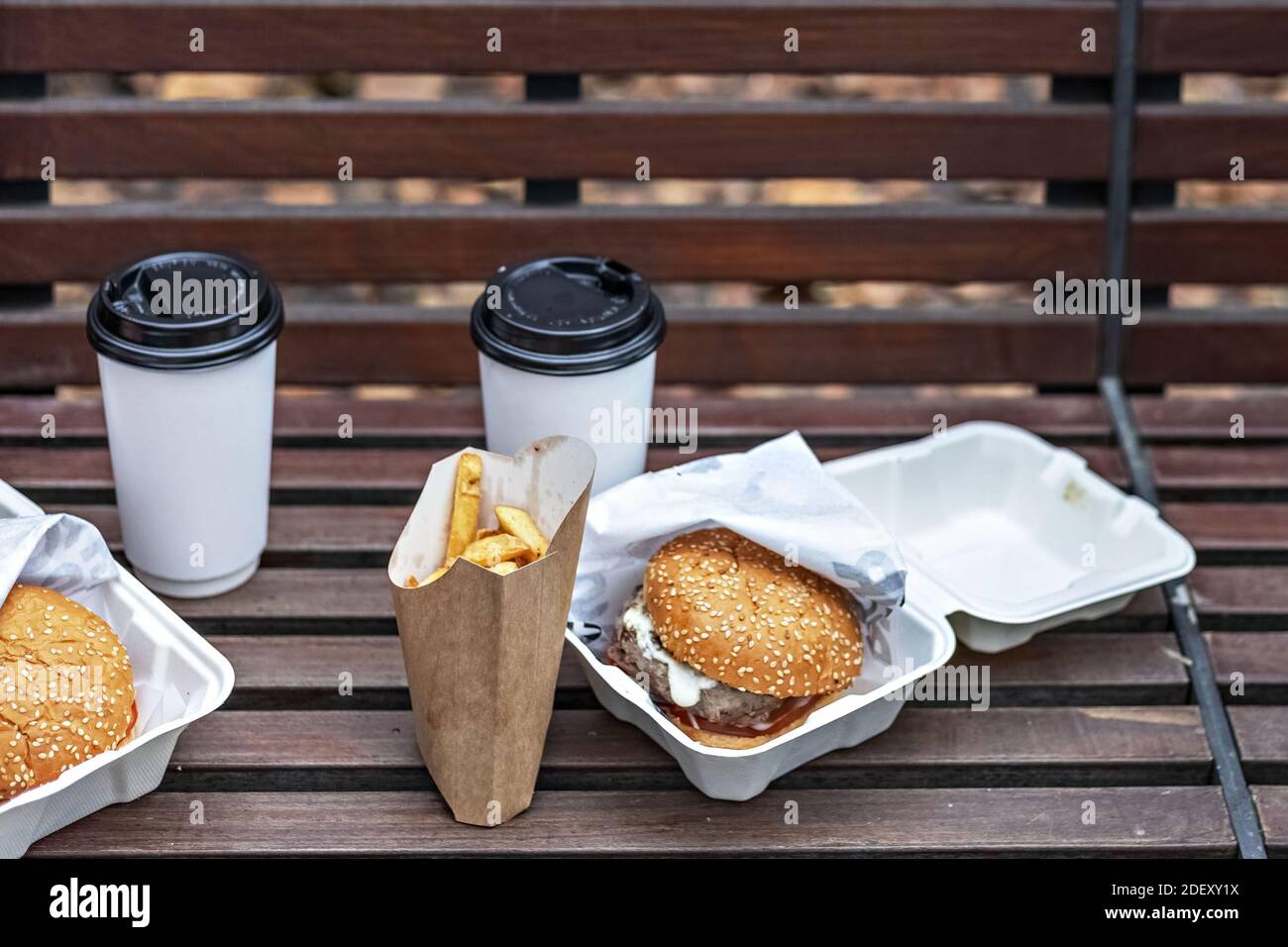 Fast food. Tazze di carta con caffè, scatole di hamburger e patatine fritte su un concetto di cibo pank.Takeaway Park. Foto Stock