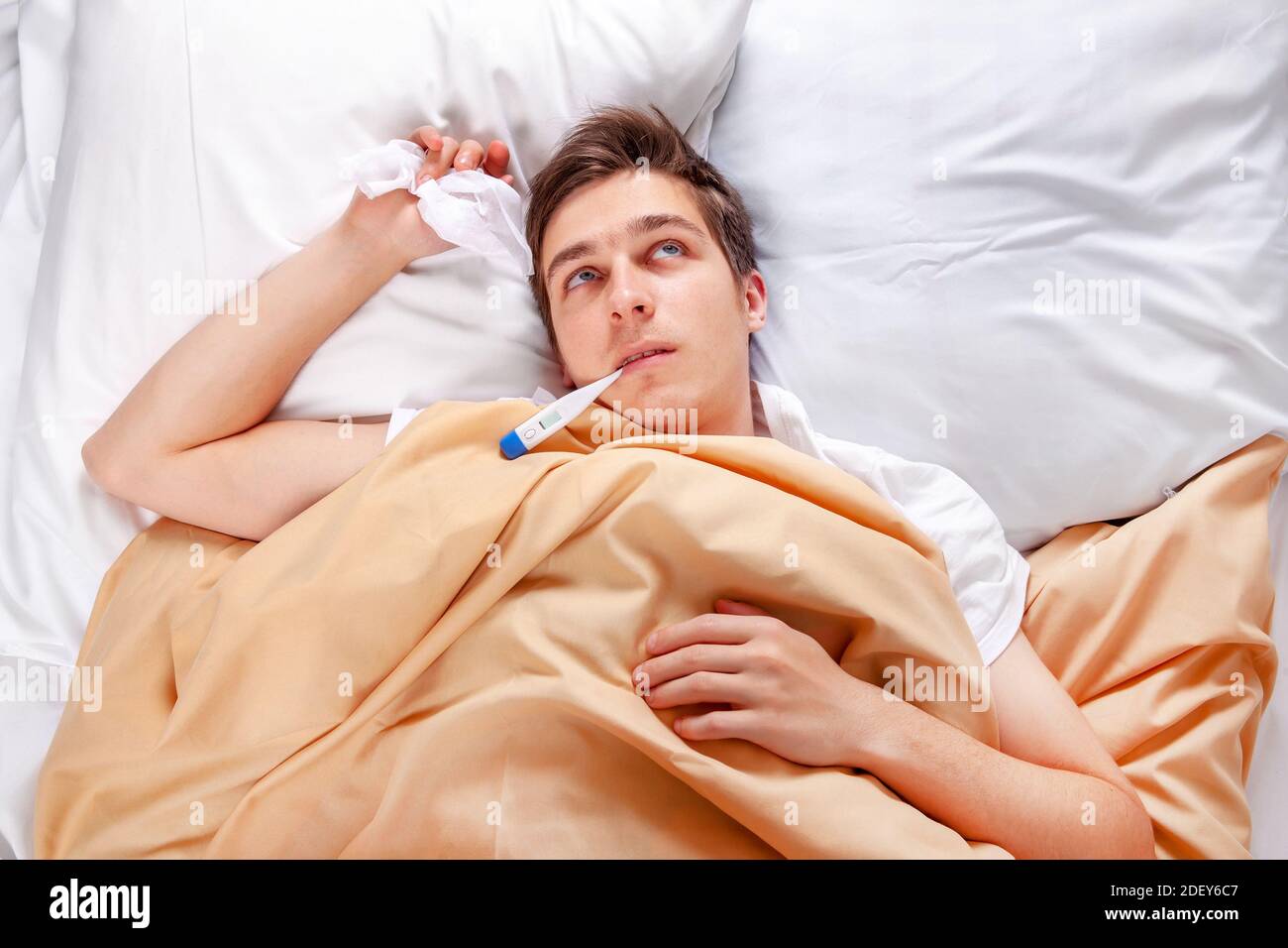 Malato giovane uomo con un termometro nel letto a. La casa Foto Stock