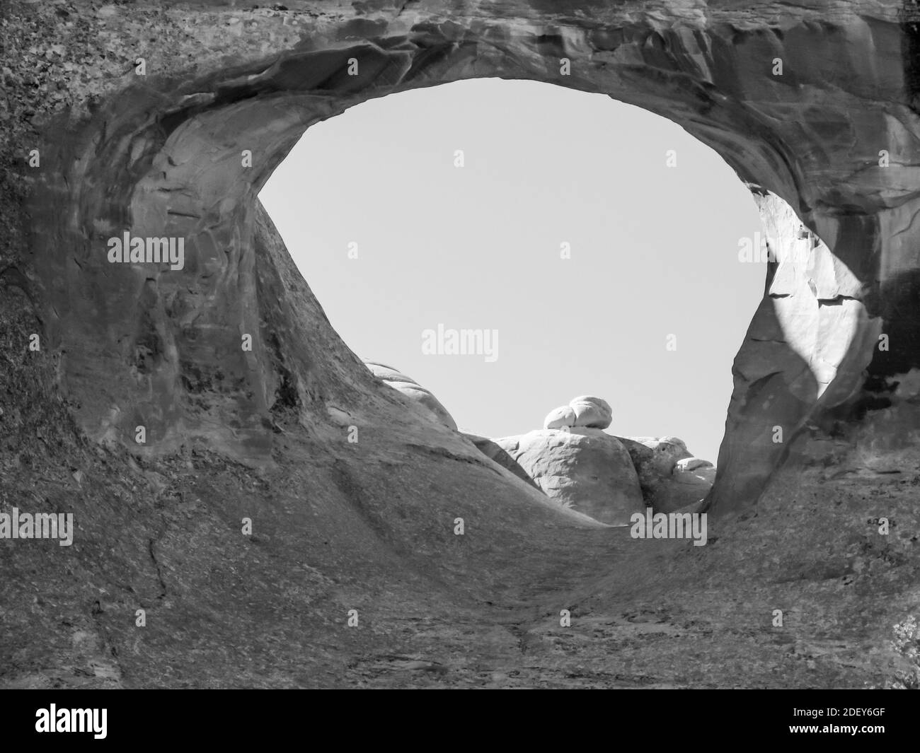 Una foto in bianco e nero di Tunnel Arch, uno degli archi più piccoli nella sezione Giardino del Diavolo del Parco Nazionale Arches, Utah. Foto Stock