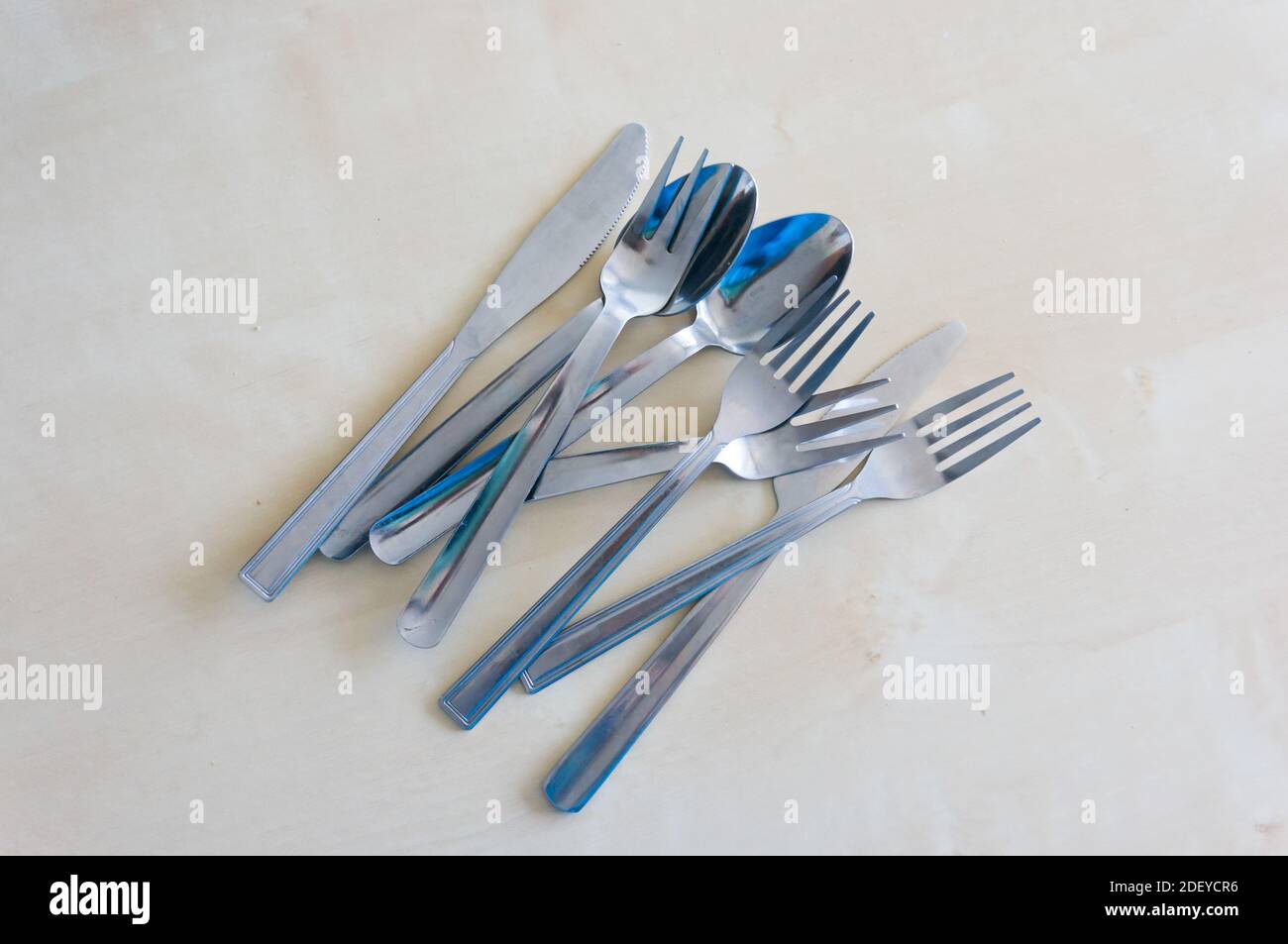 Una vista dall'alto di oggetti da tavola inclusi forchette, coltelli e cucchiai su un tavolo bianco Foto Stock