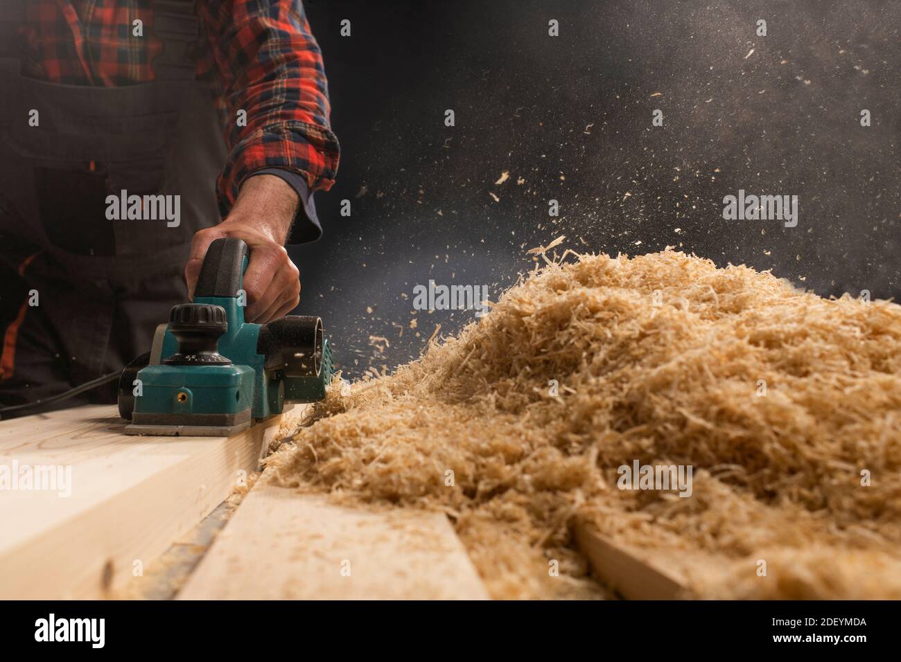 Lavoratore piallare il piano di un tavolo di legno con un piano elettrico. Foto Stock