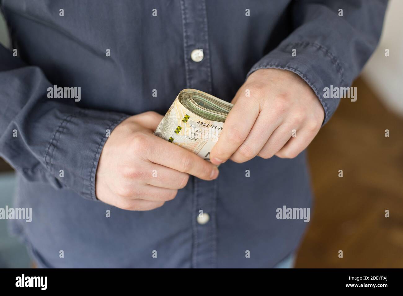 Confuso uomo con un fascio di lucidare il denaro in mano Foto Stock