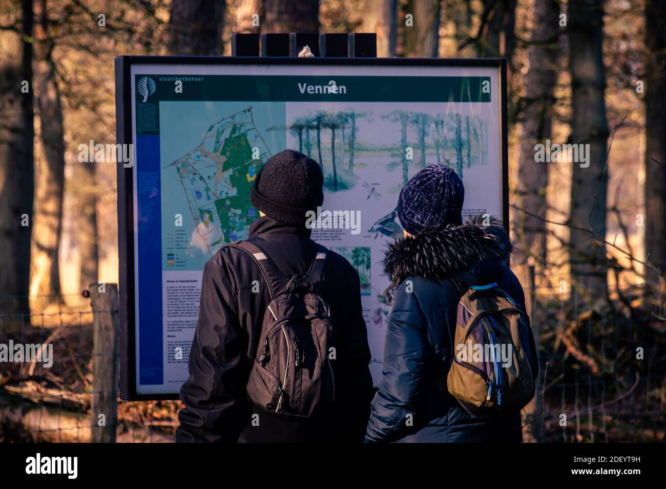 BORGER, PAESI BASSI 25 NOVEMBRE 2020.due persone con piccoli zaini, indossando spessi cappotti invernali e caldi cappelli di lana guardando le informazioni b Foto Stock