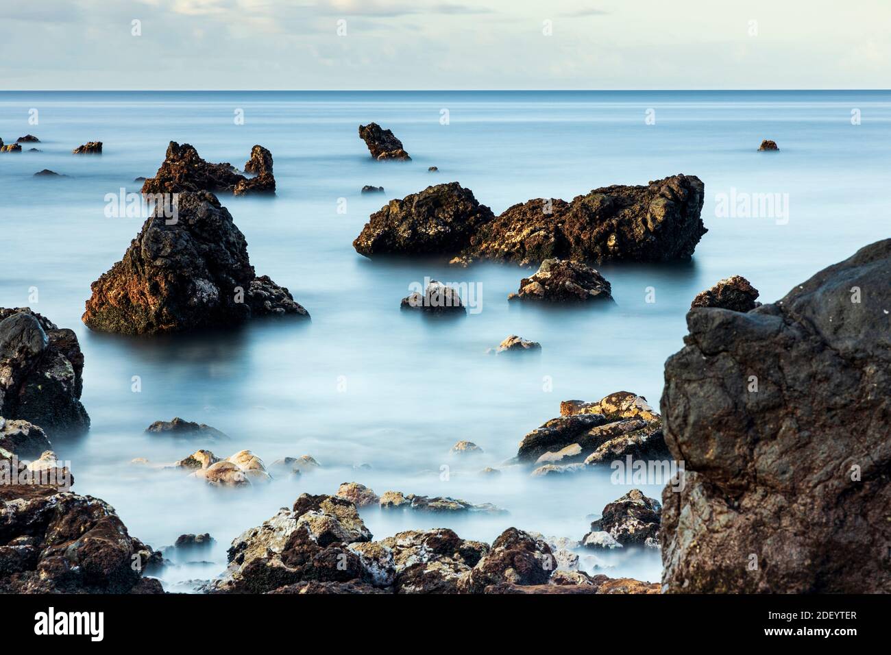 Lunga esposizione al mare all'alba con rocce a Playa san Juan, Tenerife, Isole Canarie, Spagna. Foto Stock