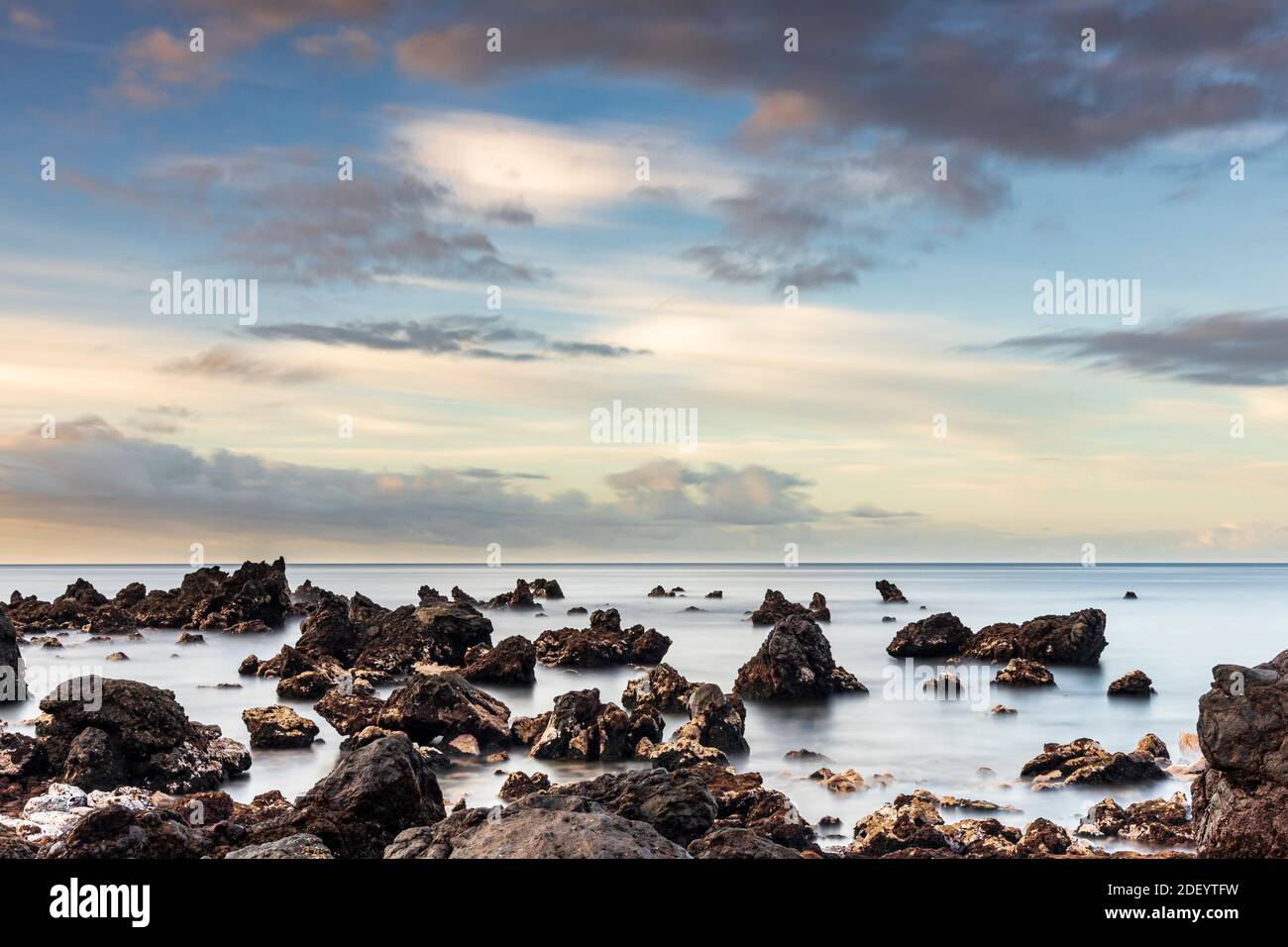 Lunga esposizione al mare all'alba con rocce a Playa san Juan, Tenerife, Isole Canarie, Spagna. Foto Stock