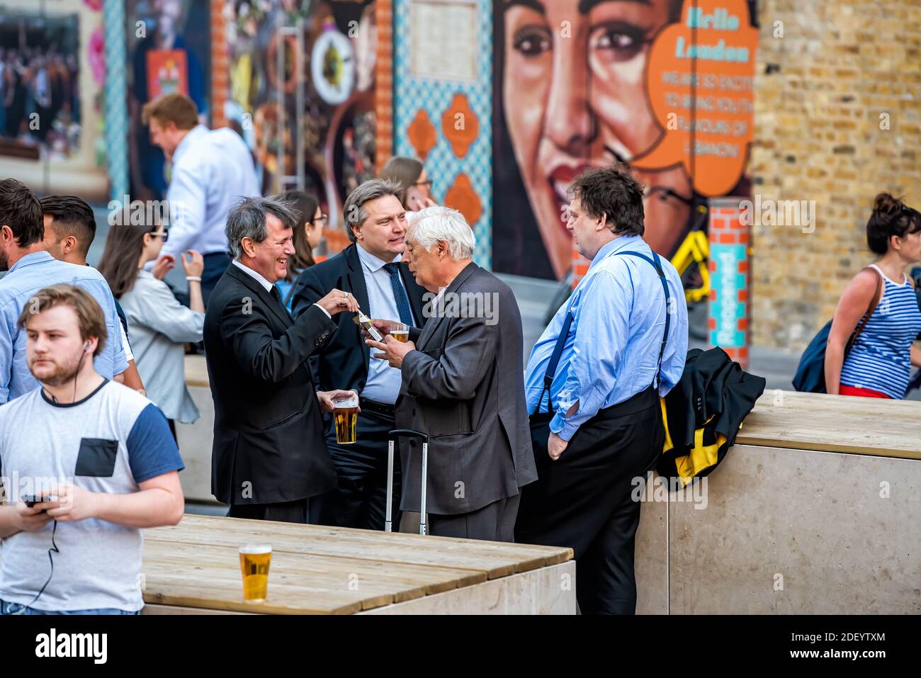 Londra, Regno Unito - 22 giugno 2018: Gruppo di molti uomini d'affari che si trovano fuori in Inghilterra al pub tavern bar Shipwrights Arms bevendo birra dalla tazza Foto Stock