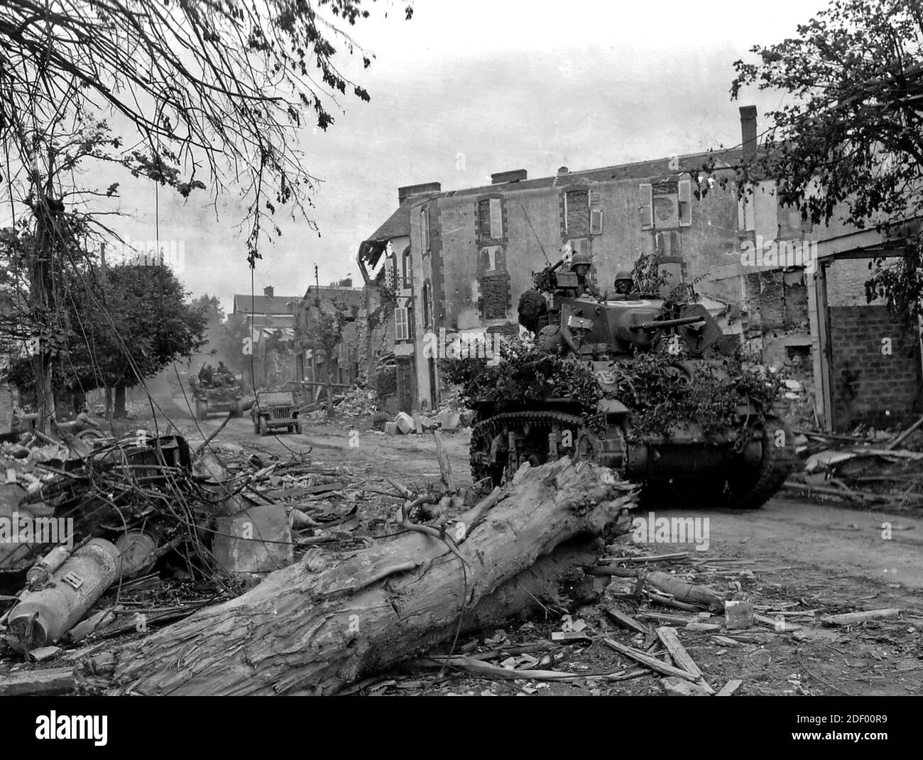 I carri armati statunitensi passano attraverso una strada distrutta a Coutances, in Normandia, nel loro viaggio verso il mare oltre la città. Coutances, catturato dalle truppe americane il 29 luglio 1944, è circa 18 miglia ad ovest di St. Lo ed è stato la chiave per le vie di fuga per migliaia di soldati tedeschi inceminati in più a nord Foto Stock