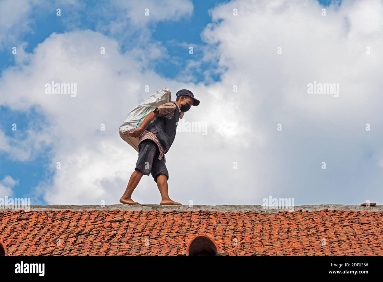 Uomo che trasporta il carico che cammina su un tetto della casa, Kathmandu, Nepal Foto Stock