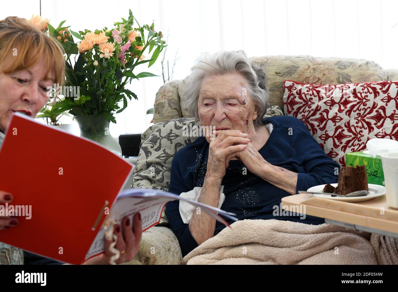 Donna che legge alla sua madre anziana che celebra il suo 104th compleanno in casa di cura Gran Bretagna, Regno Unito. Foto Stock