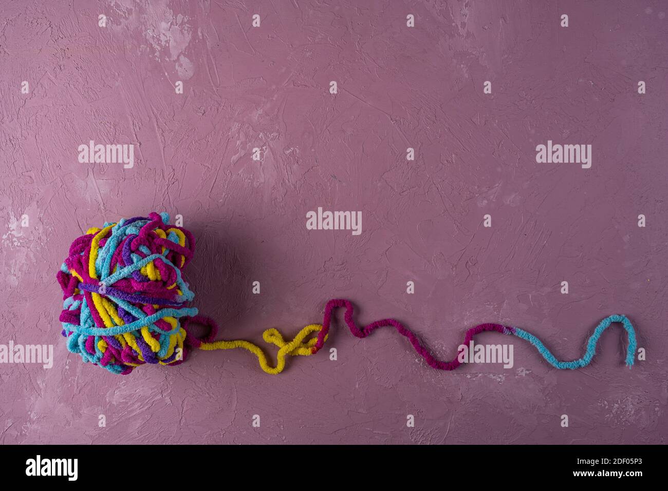 una palla di fili multicolore per lavorare a maglia su un rosa sfondo Foto Stock