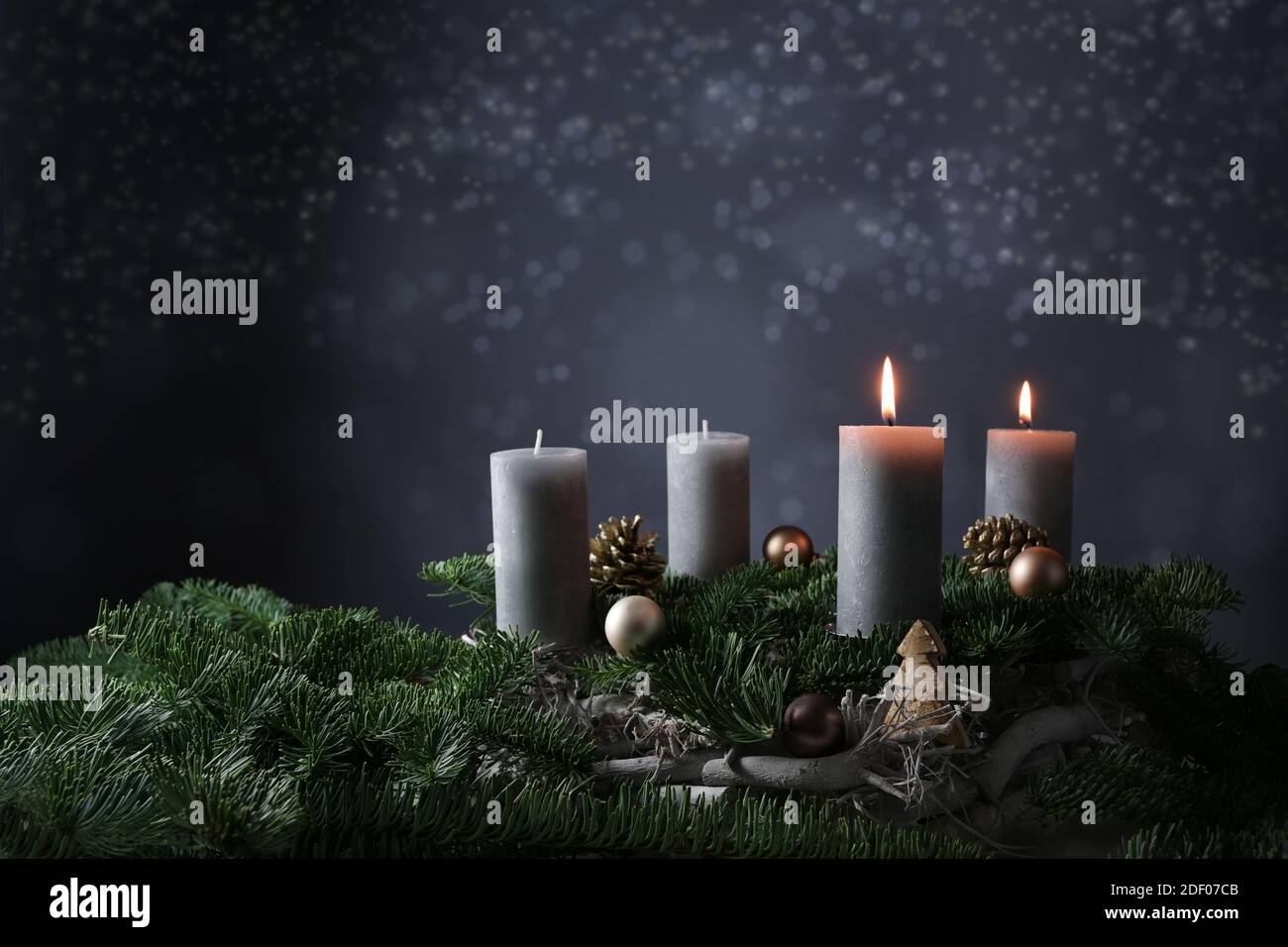 Secondo avvento con due candele brucianti su rami di abete con decorazione di Natale contro uno sfondo grigio scuro, spazio di copia, fuoco selezionato, stretto de Foto Stock