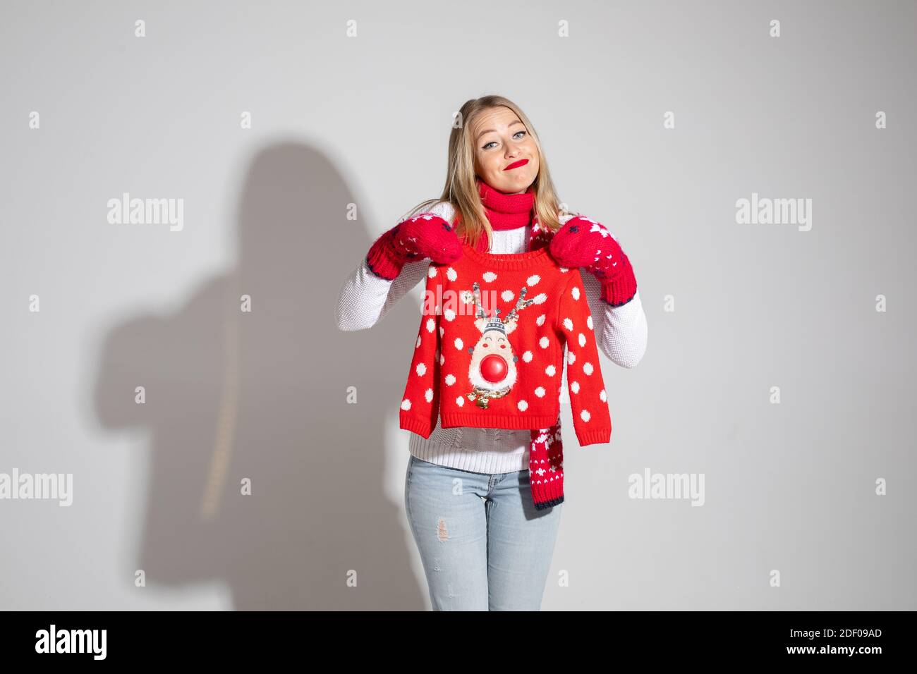 Signora bionda confuso che posa con il maglione di Natale Foto Stock