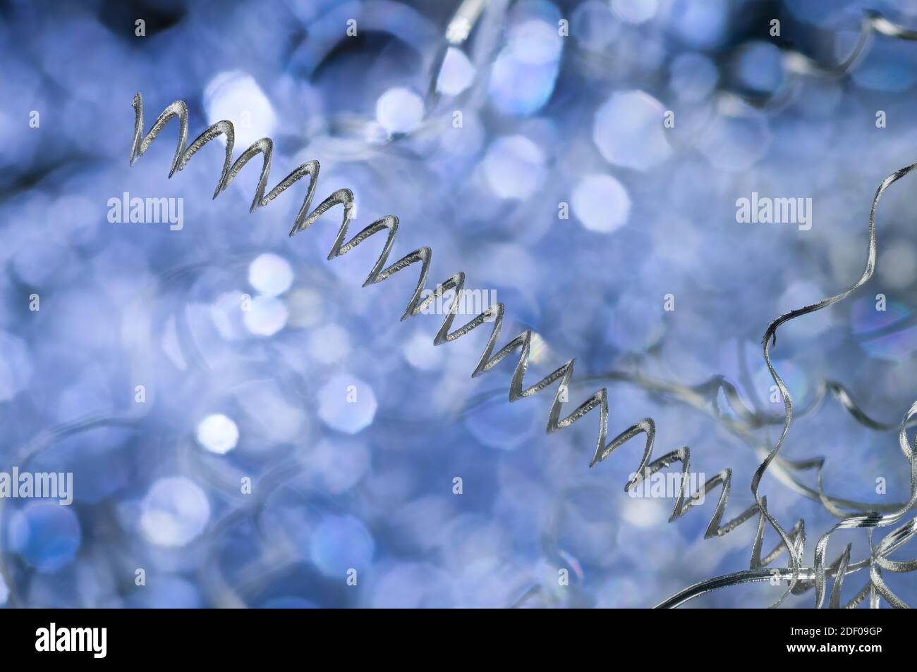 Dettaglio di sfridi in alluminio ritorto a spirale lunga su sfondo blu. Closeup di rifiuti metallici in tornitura. Sottoprodotto lavorazione truciolo. Ingegneria meccanica. Foto Stock