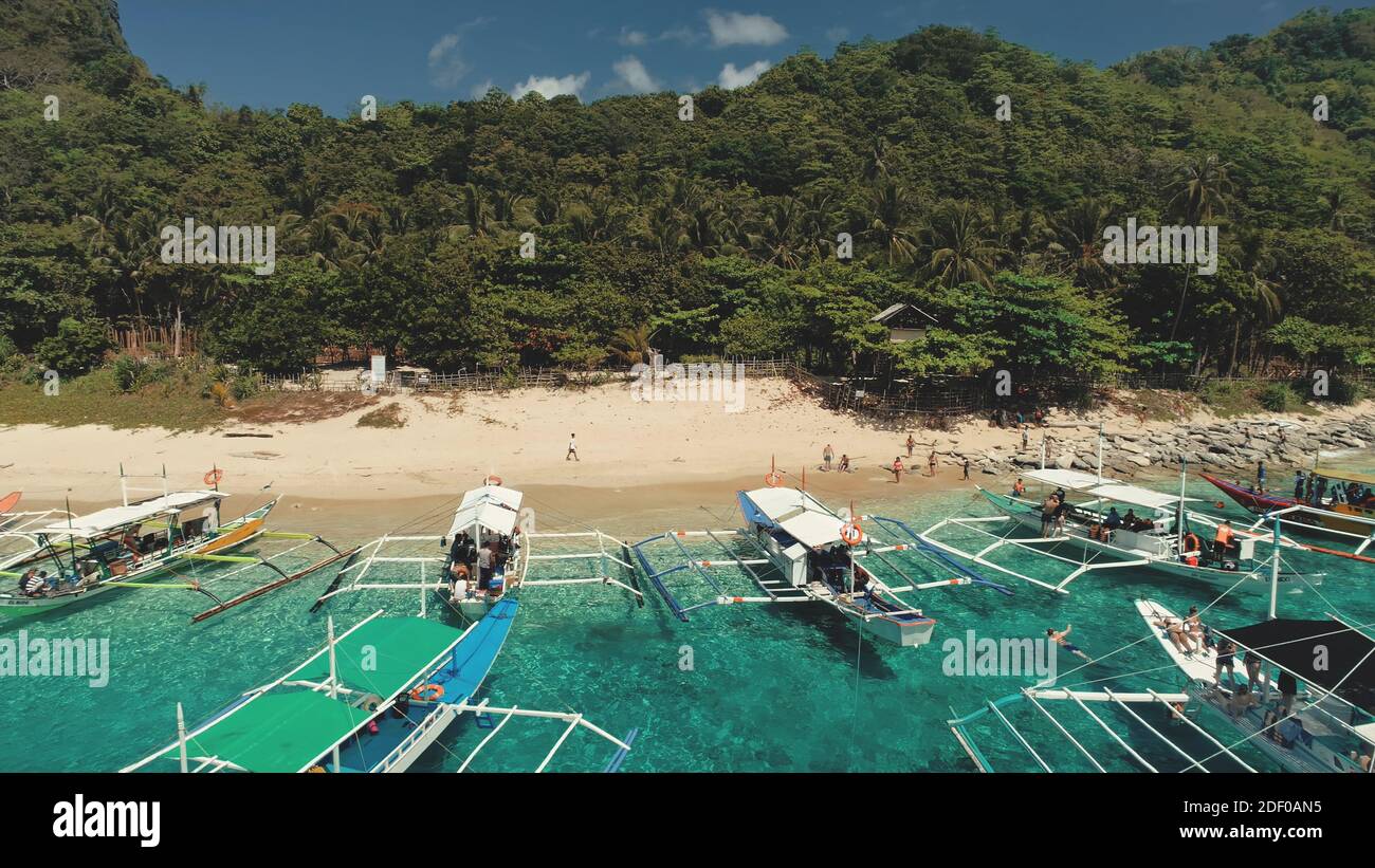 Turisti crociera oceanica: Barche passeggeri al porto di mare baia. Resort tropicale Filippine con spiaggia di sabbia bianca al porto costiero. Paesaggio asiatico dell'isola di Palawan per i viaggiatori in film cinematografico drone Foto Stock