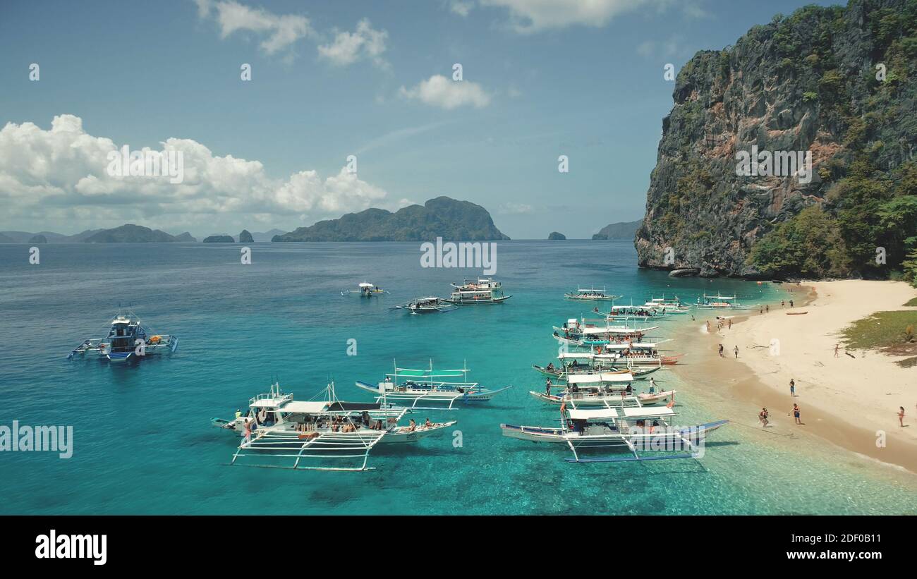 Vista aerea delle barche passeggeri con i turisti riposano sulla spiaggia di sabbia marina dell'isola di Palawan, Filippine, arcipelago di Visayas. Tropic natura altopiano paesaggio con foresta verde durante il giorno d'estate Foto Stock