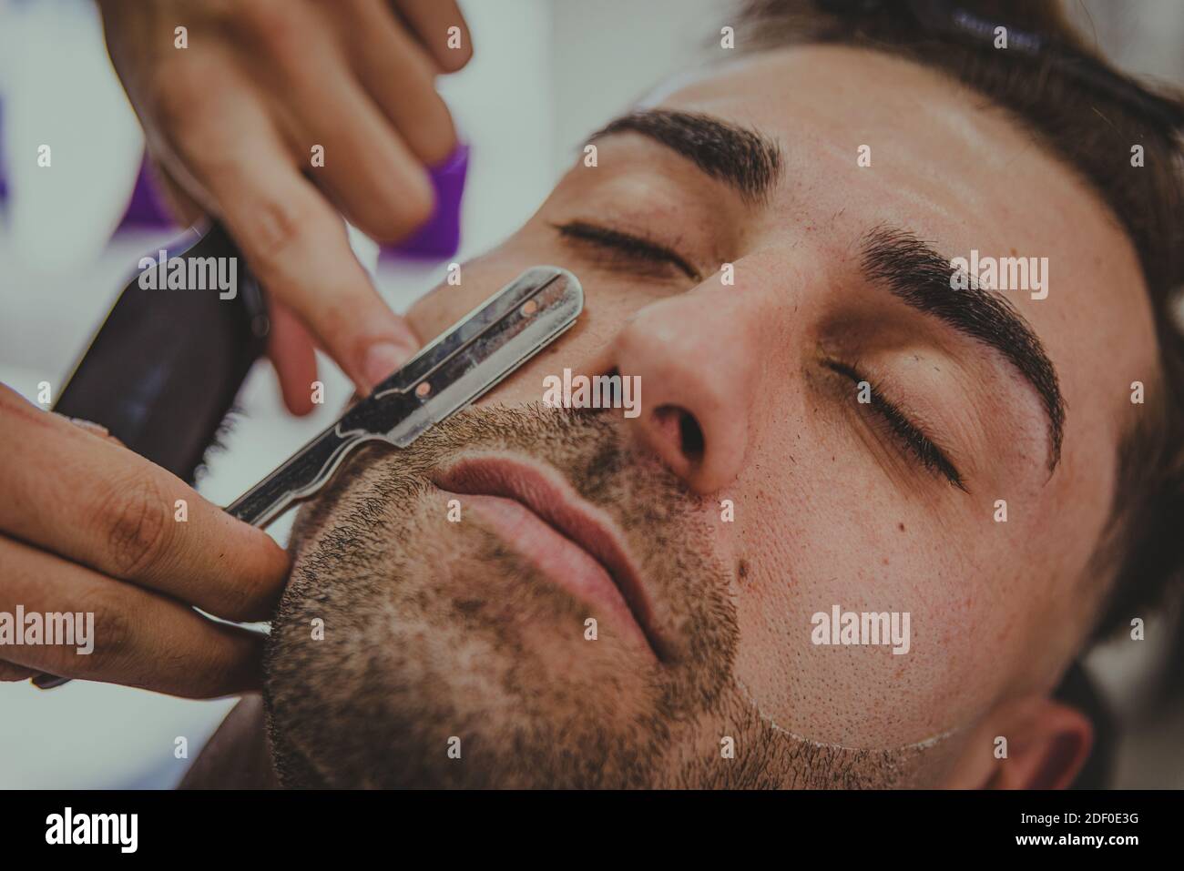 particolare di un giovane con le braccia tatuate taglia a. i capelli dell'uomo in un barbiere Foto Stock