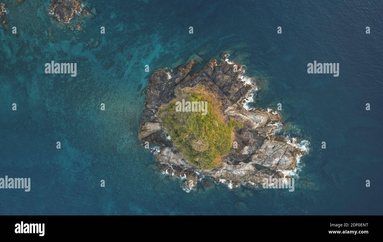 In cima a un'isola rocciosa con un'antenna a picco verde. Nessuno paesaggio naturale di El Nido Islet, Filippine, Asia. Onde oceaniche alle scogliere. EPIC baia di mare con isola verde. Alberi esotici tropicali in cima alla roccia Foto Stock