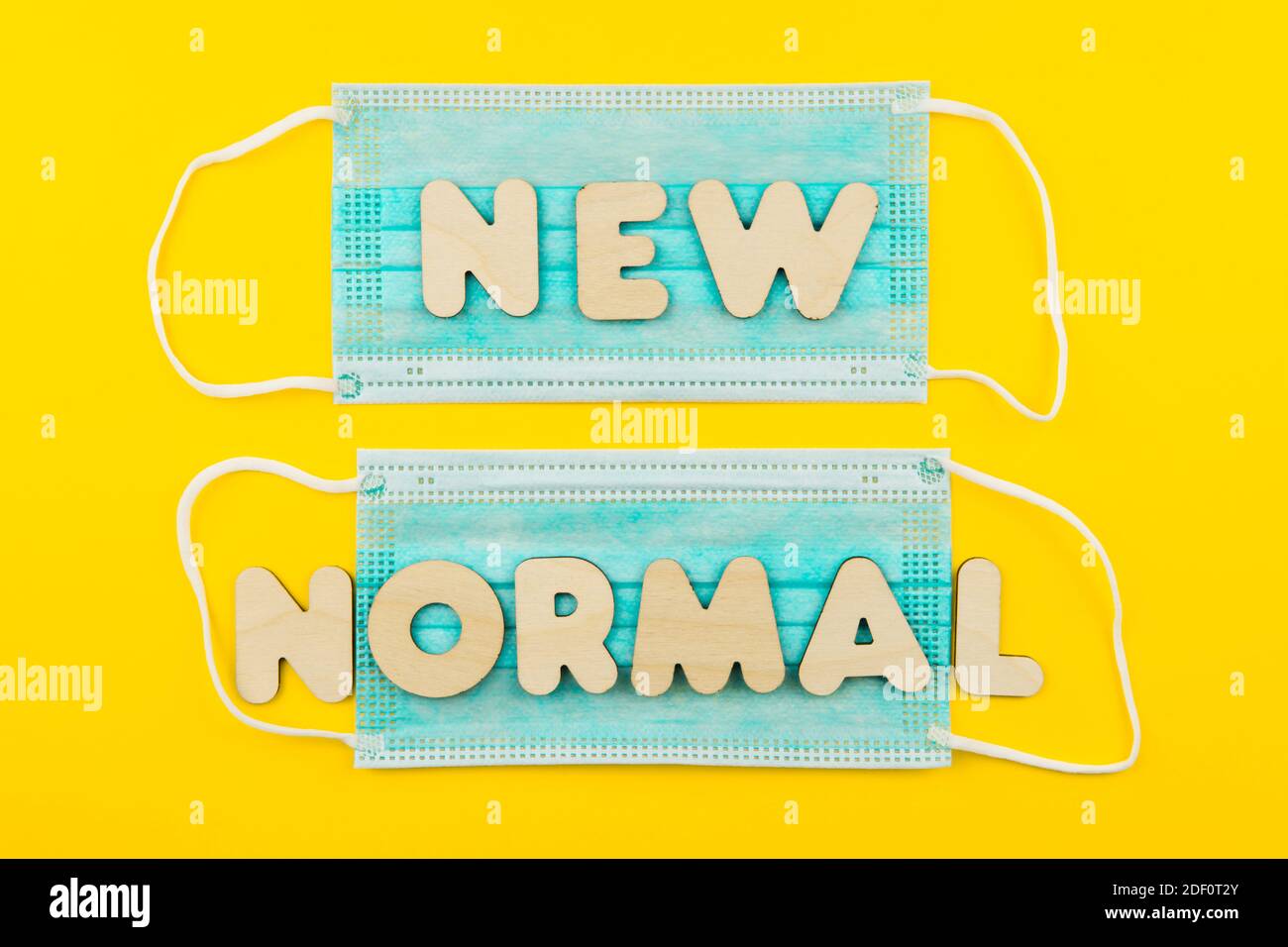 NUOVE parole NORMALI sulle maschere facciali di protezione su sfondo giallo. Post covid-19 pandemie cambiamenti, nuova realtà, indossare maschera in pubblico concetto. Foto Stock