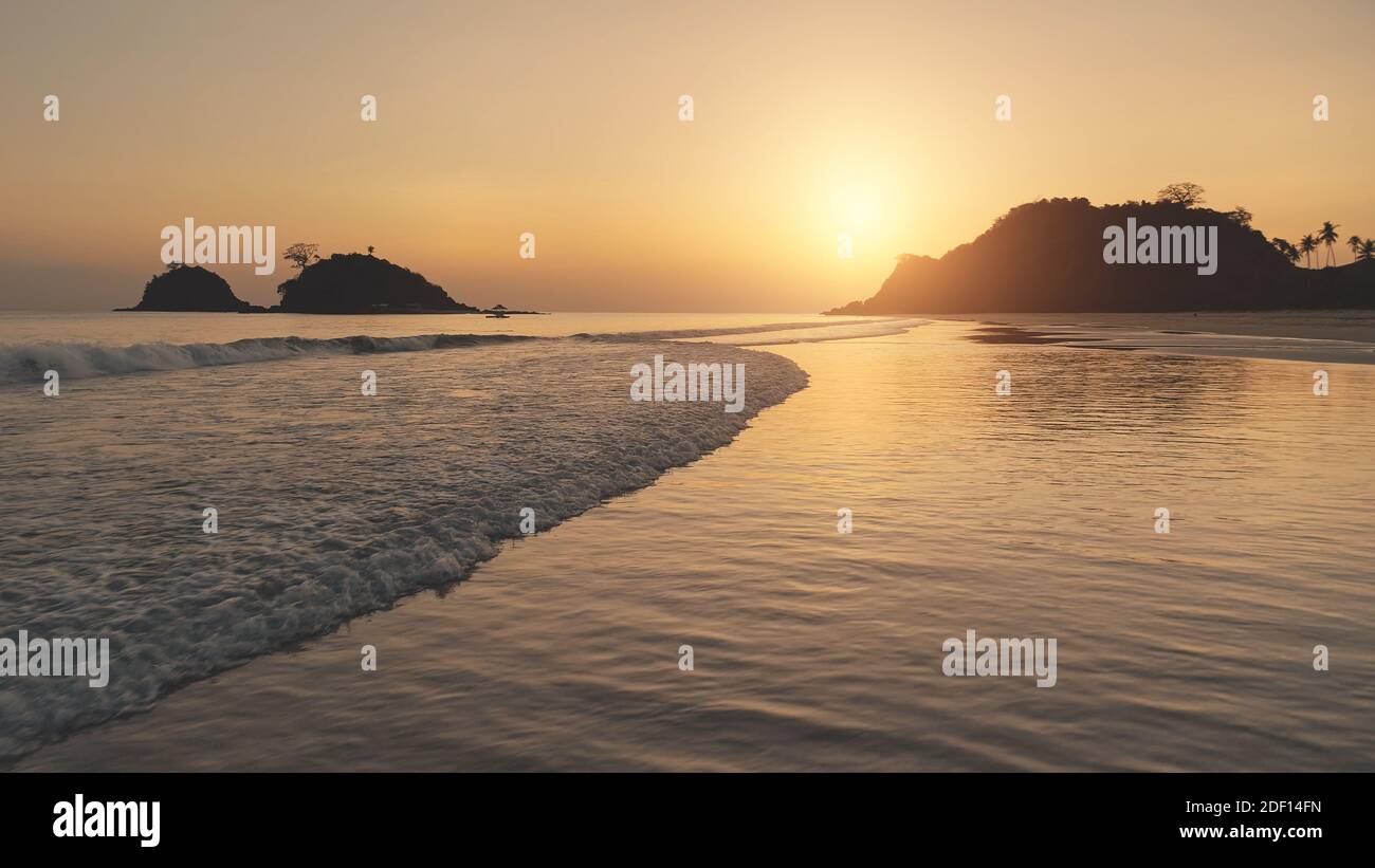 Tramonto in aereo alle onde dell'oceano. La silhouette del sole dell'isola di montagna paradisiaca alla baia del mare ondulata. Acqua in crash. Tropic natura stagcape a El Nido isolotto, Filippine, Asia a vista aerea Foto Stock