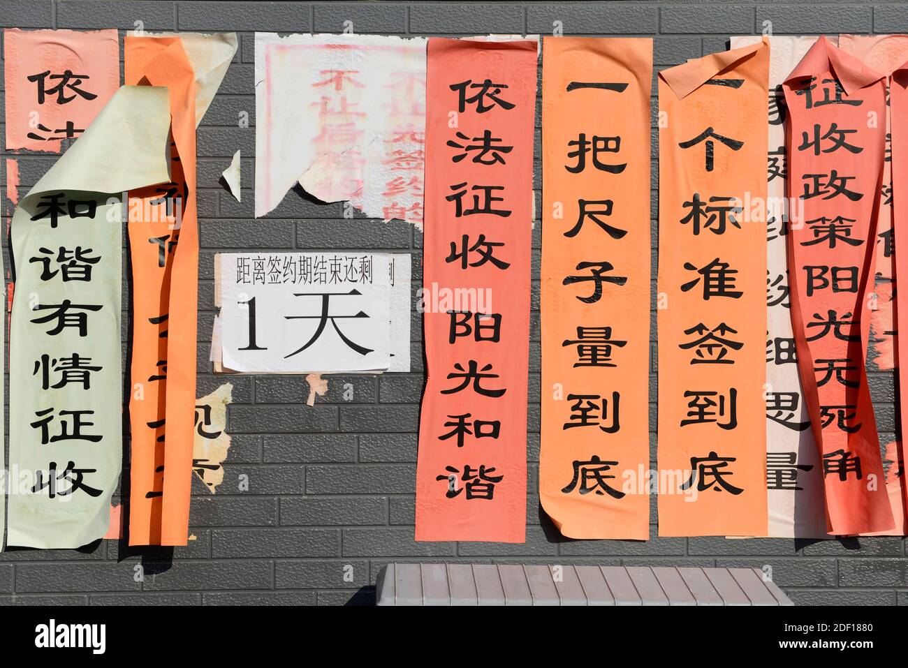 Bandiere che richiedono l'adesione e l'attuazione delle regole sono pubblicati su negozi illegali da demolire nel centro occidentale di Pechino, Cina Foto Stock