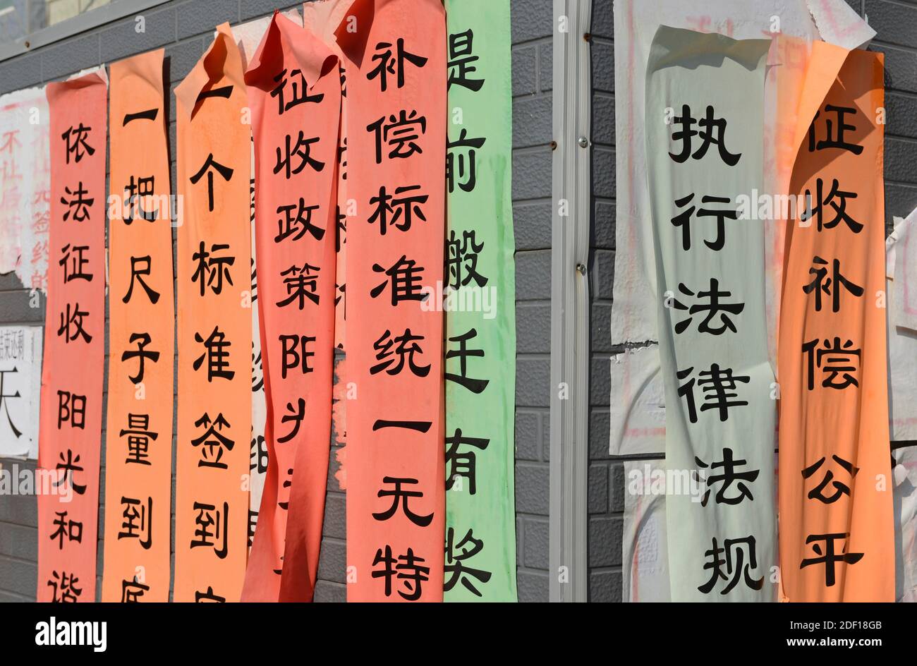Bandiere che richiedono l'adesione e l'attuazione delle regole sono pubblicati su negozi illegali da demolire nel centro occidentale di Pechino, Cina Foto Stock