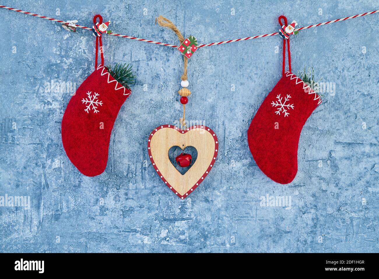 Sfondo di Natale. Calze natalizie rosse e cuore appeso su corda su sfondo blu. Spazio di copia. Foto Stock