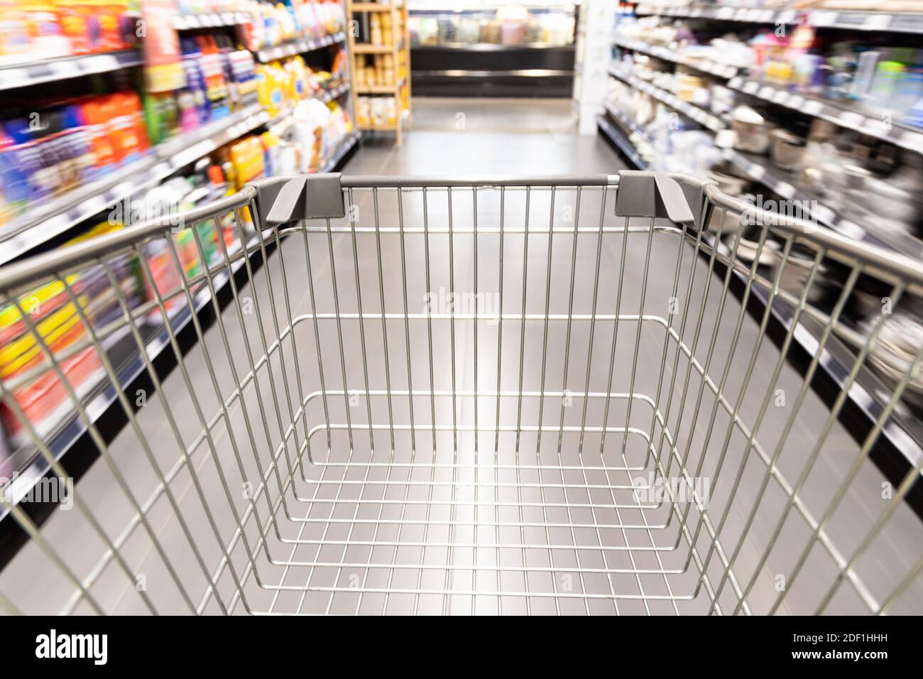 Carrello carrello di shopping che si muove in supermercato con movimento blur corsia sfondo Foto Stock