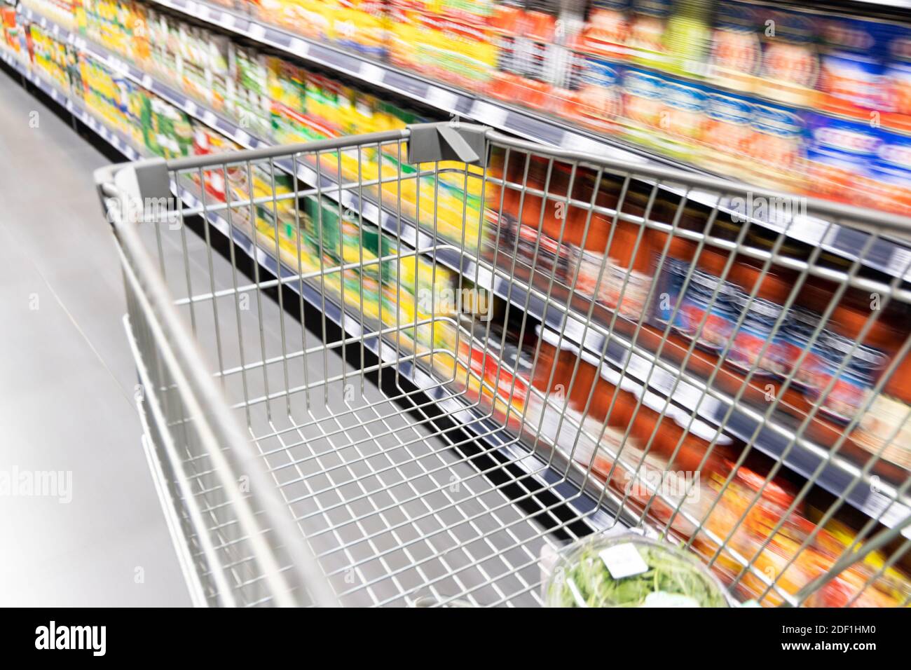 Carrello carrello di shopping che si muove in supermercato con movimento blur corsia sfondo Foto Stock