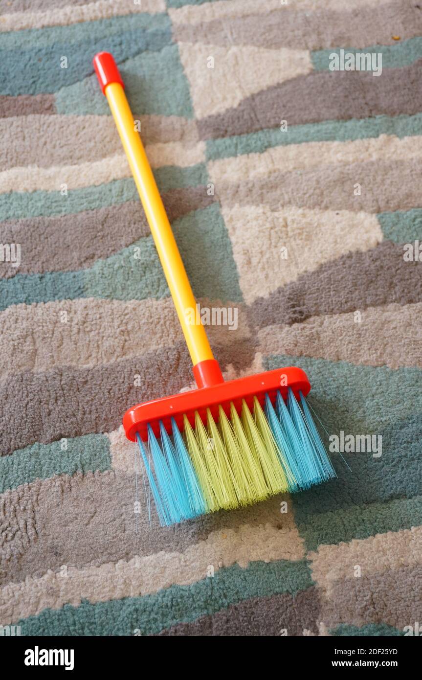Una scopa a spinta di diversi colori su un multicolore moquette Foto Stock