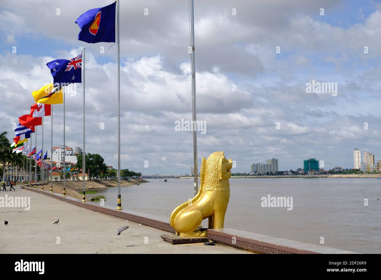 Cambogia Phnom Penh - passeggiata Riverside Park con internazionale nazionale bandiere e la statua del leone del guardiano dorato Foto Stock